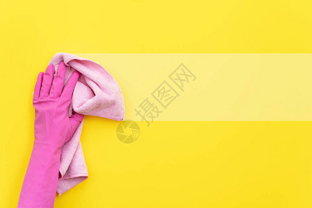 戴橡皮手套手握粉色和软清洁毛巾的女士在黄色背景上孤立图片