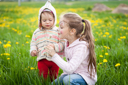可爱姐妹吹花朵在草原上享受夏图片