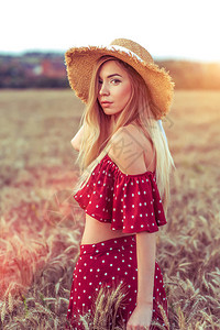 夏天在小麦田里的女孩穿着红礼服和草帽女人穿过田野图片