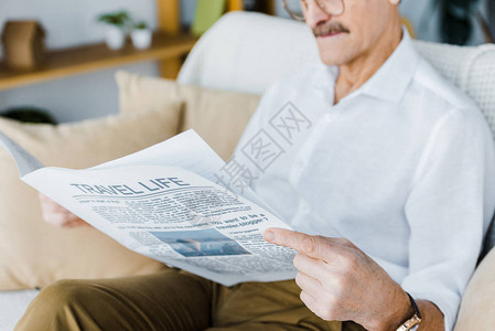 老人坐在沙发上看旅游报纸时的景图片
