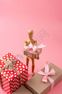 以粉红背景持有礼物的木玩具模型图片