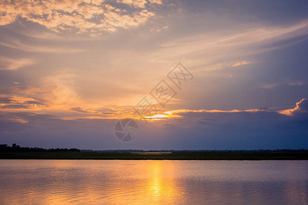湖面风景背上方云层后面的美丽的日落下图片