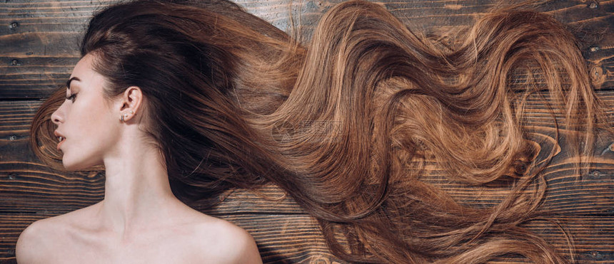 美丽的长头发在木制背景上的女人长发时髦的发型图片