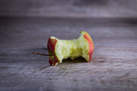 被咬的苹果躺在木制的背景上图片