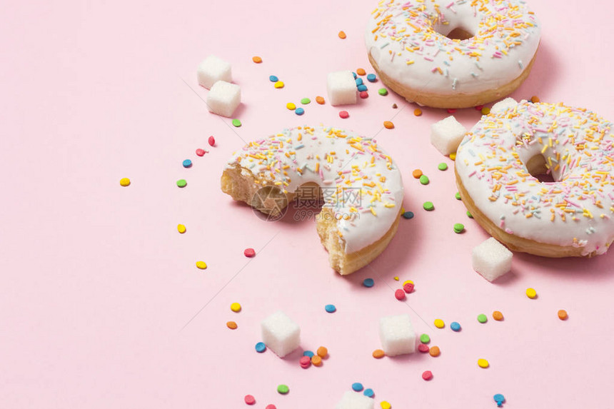 新鲜美味的甜圈五彩装饰糖果粉红色背景上的方糖面包店概念新鲜糕点美图片