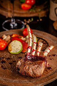 烤羊排配烤蔬菜和覆盆子酱用一杯红酒在木板上端菜餐厅里的美味佳肴背景图图片