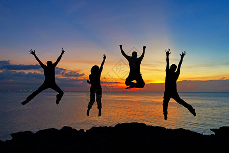 朋友和团队合作在日落时间在海滩上跳跃以取得成功的剪影生活方式和图片