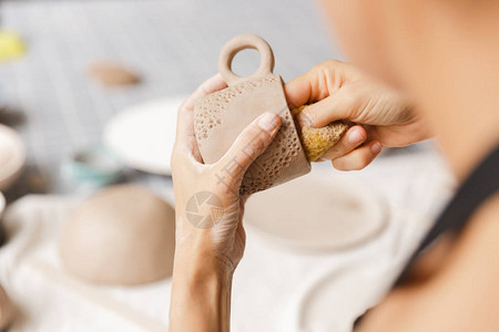 一位在车间制作陶瓷和陶瓷餐具与粘土一起工作图片