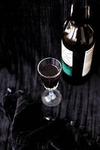 黑色背景上的瓶子和一杯红酒图片
