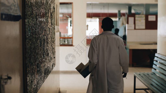穿着白色医用长袍的非洲医生穿过非洲村庄的医院大厅急诊科图片