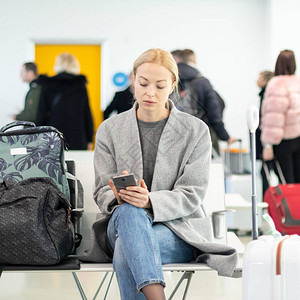 身着金发的年轻女子在机场终点站出发门等候登机时图片