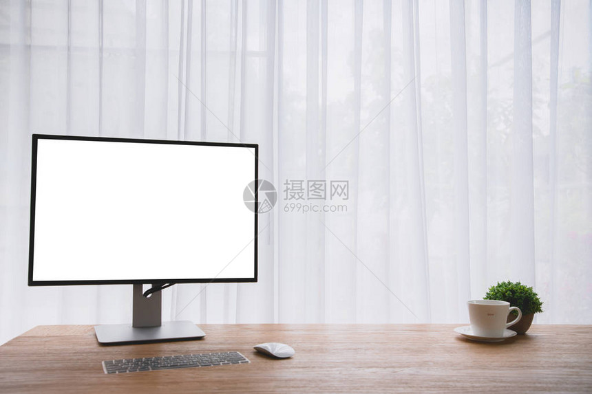显示器计算机屏幕上有空白屏幕的木制办公桌和白色窗帘纹理背景上的咖啡杯图片