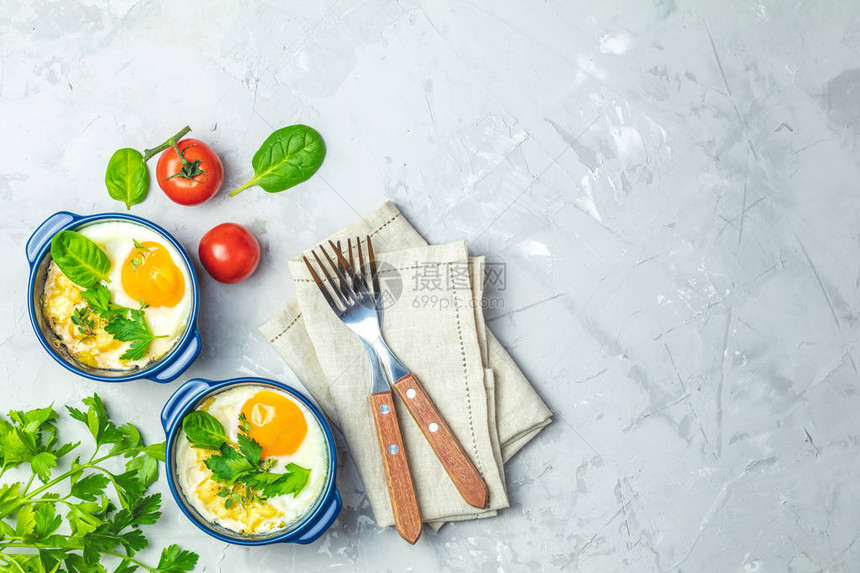在蓝色陶瓷烘焙模具中的烤鸡蛋意大利或法式风格的蔬菜和鸡蛋分份砂锅鸡蛋kokotcocotte早餐顶视图图片