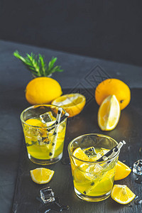 柠檬酒精在黑石块混凝土表面用冰柠檬和迷迭香草喝鸡尾酒图片