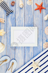 柔和的蓝色木板背景上毛巾人字拖贝壳和海星的顶部视图图片