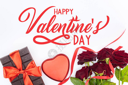 由节日丝带红玫瑰和心形礼物盒包着的巧克力顶部景色图片