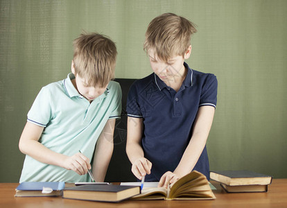 两兄弟在办公桌前做作业一位兄弟正在帮助并解释图片