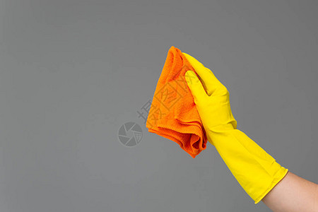 橡皮手套的一只手在中背景上拿着一个亮显微纤维粉尘机图片