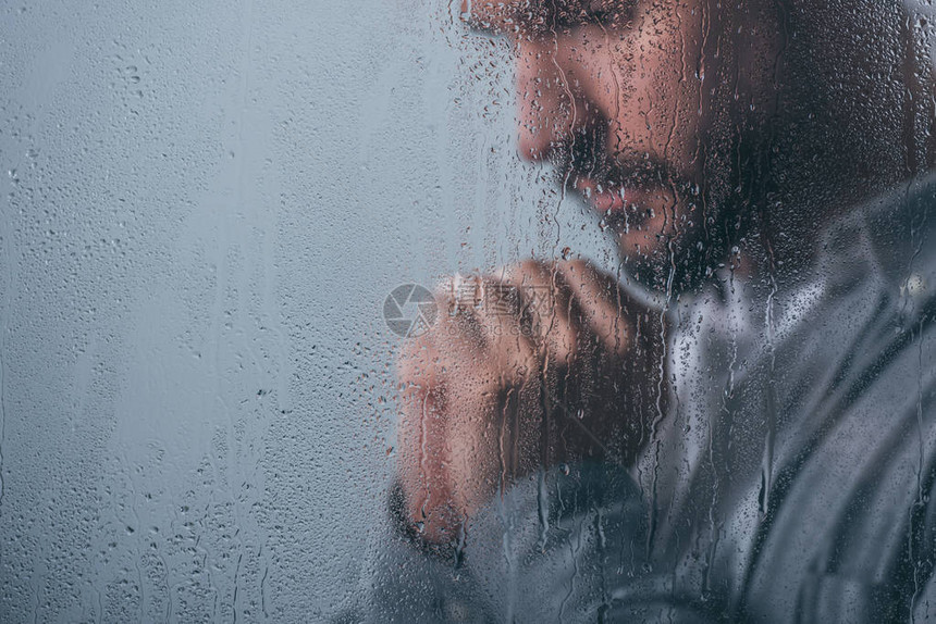 男人用折叠的手在窗口中哭泣用雨图片