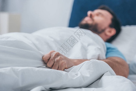 男人躺在床上拿着毯子图片
