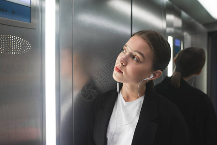差事年轻的女上班族站在电梯里背景