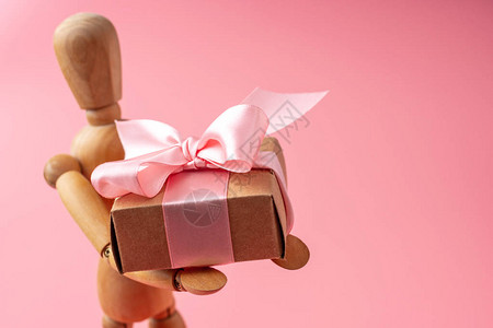 以粉红背景提供礼物的木玩具模型图片