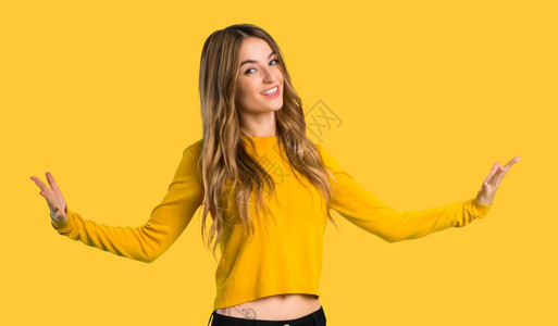 身穿黄色毛衣的年轻女孩在孤立的黄色背景中自豪和自满地图片