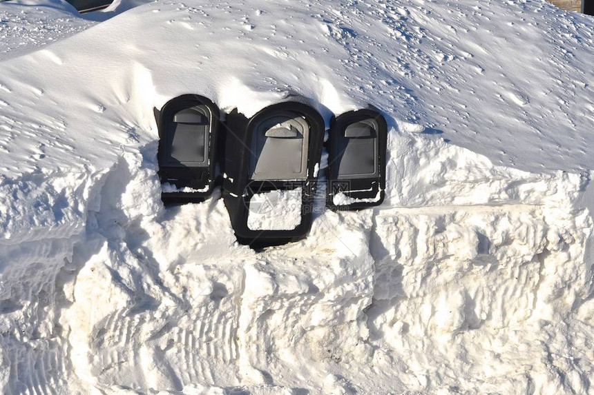 几乎被埋在雪地里的邮箱需要挖掘才能在暴风雪后图片