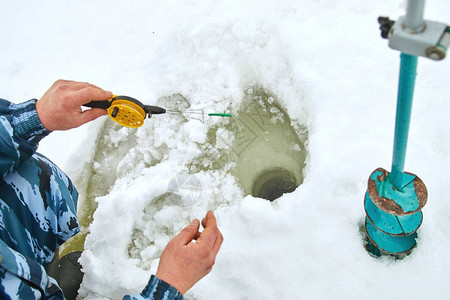 一个人在冰上的洞里钓鱼冬季捕图片