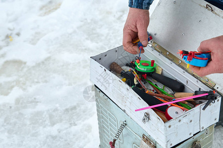 渔夫在冬季捕鱼时捡起钓鱼的钩子装有渔具图片
