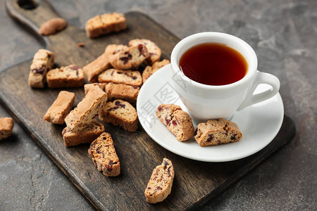 在灰色的桌子上喝杯茶和美味的意大利脆饼图片