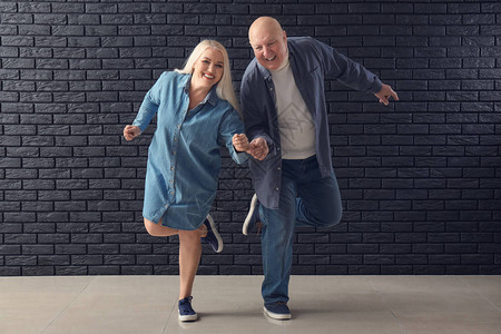 可爱的老夫妇在黑砖墙上跳舞图片