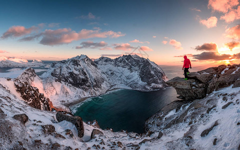 男子登山者在日落时站在山顶的岩石上图片