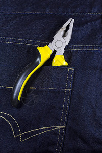 蓝色牛仔裤口袋中的黄色钳子用于一般维修图片
