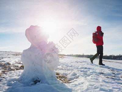 年轻人在雪地上的春天景观中走到融化的播种人徒步旅行者背着包图片