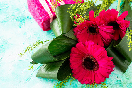 母亲节背景或贺卡热贝拉红花布和绿宝石桌上的礼物图片