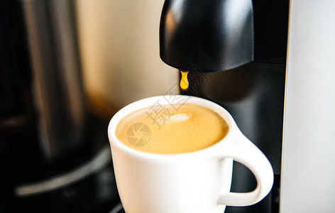 美味的咖啡从咖啡浓缩咖啡机倒在白色豪华瓷杯中图片