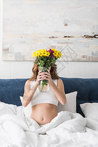 孕妇坐在床上手里拿着花瓶图片
