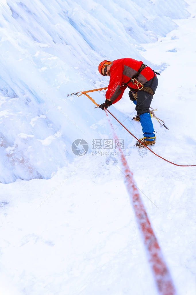 登山者在降雪期间穿越冰川的冰墙图片