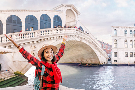 快乐的亚洲女欣赏威尼斯大运河上著名桥梁的图片