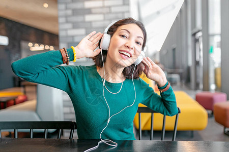 快乐的亚洲女人享受音乐用耳机和在酒店大厅图片