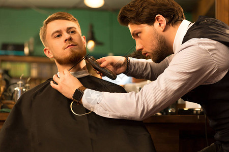 年轻人在理发店服务客户消费主义豪华福利舒适理发专业时髦的专业理发师剃图片