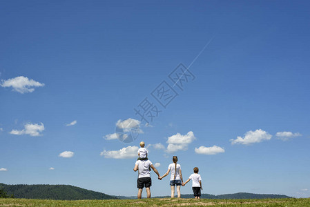 父亲母亲和两个小儿子正站在一片绿地上图片