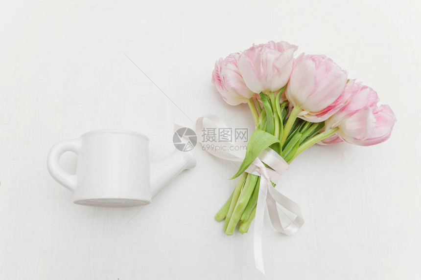 春天贺卡一束新鲜的淡粉色郁金香花小玩具喷壶白色背景上的花瓶节日快乐情人节概念平躺顶图片