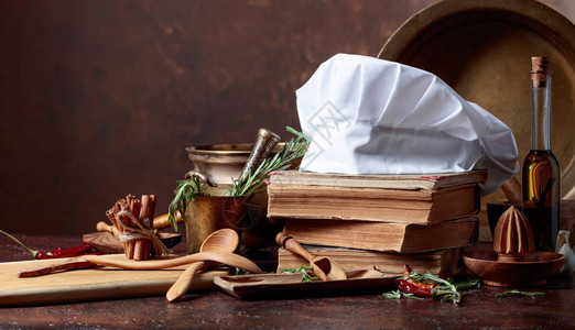 白色厨师帽和旧食谱厨房用具香料和迷迭香在厨房的桌子图片
