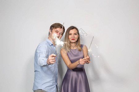 派对家庭和假期概念年轻夫妇用白色背景的烟火庆祝他们图片