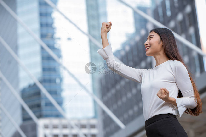 妇女举起手来争取商业赢家成功的概念图片