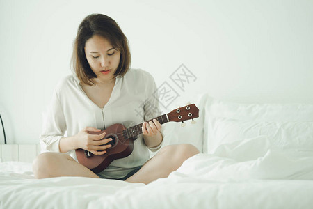 亚洲女孩从早上醒来起就弹吉他图片