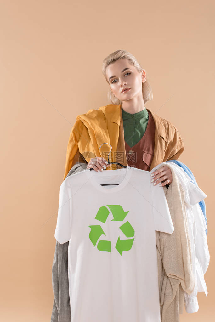 身着生态服装在蜜蜂边隔离的衣架上挂有回收标志的美丽年轻美女图片