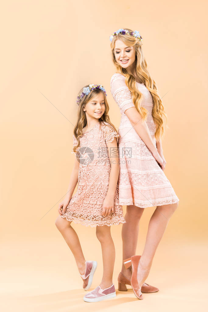 穿着优雅拉西礼服和花圈的妈和女儿背对图片